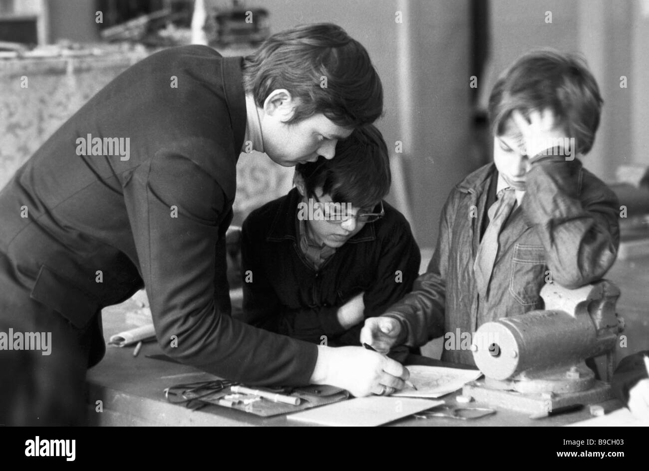 A teacher giving machine turning classes to five graders at secondary