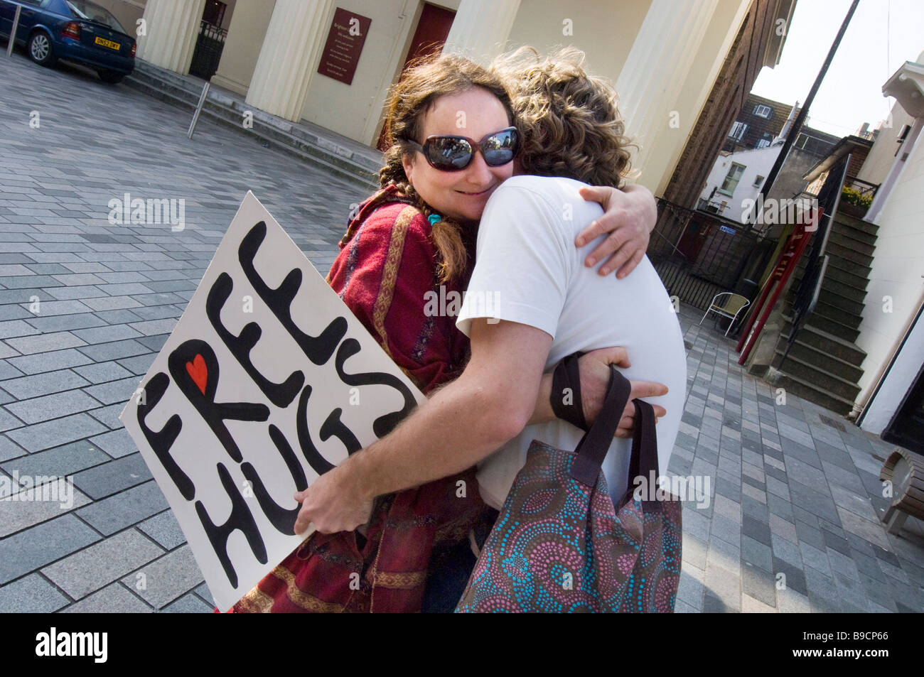 A young couple give each other a spontaneous hug in central Brighton East Sussex Stock Photo