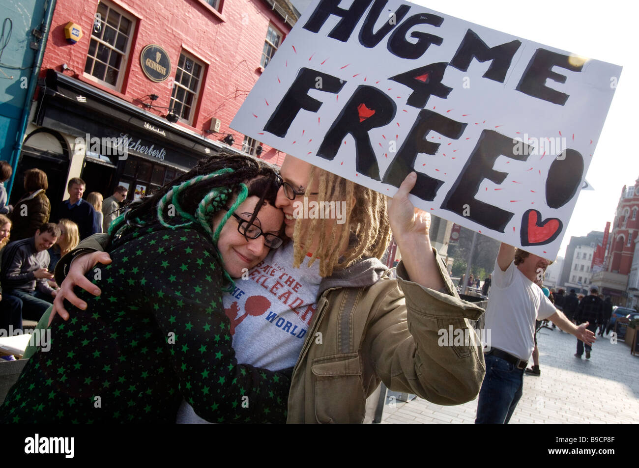 A young couple give each other a spontaneous hug during a Free Hugs day in Brighton Stock Photo