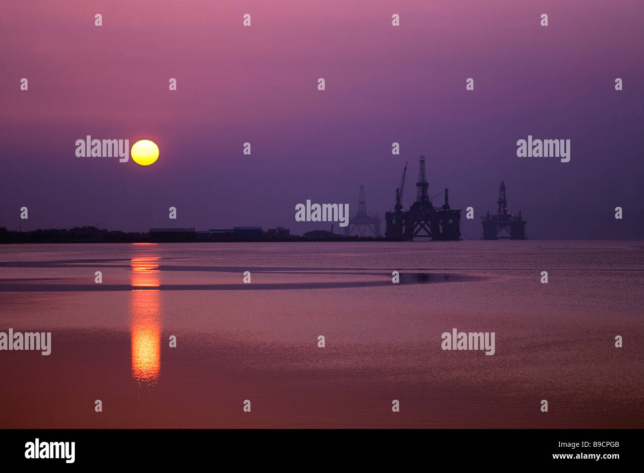Twilight crepuscular rays and Purple Dawn sunrise at Invergordon. North Sea Drilling rigs in the Cromarty Firth port facility in Northern Scotland, UK Stock Photo