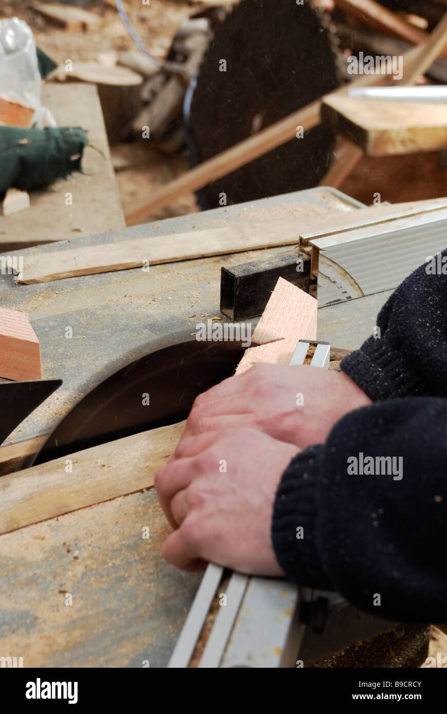 Man operating circular saw crosscutting angled timber components Stock