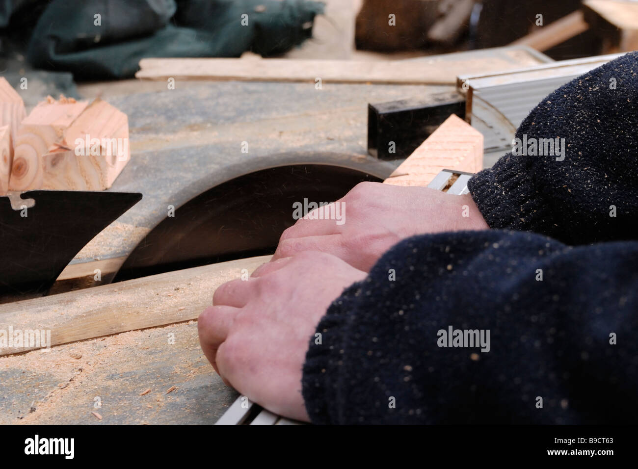 Man operating circular saw crosscutting angled timber components Stock