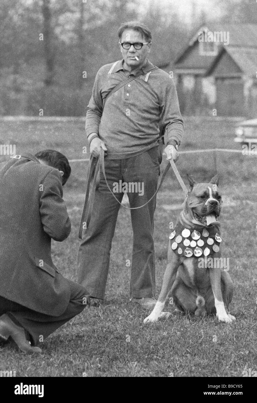 A dog breeder with a medalist boxer participant of a dog show Stock