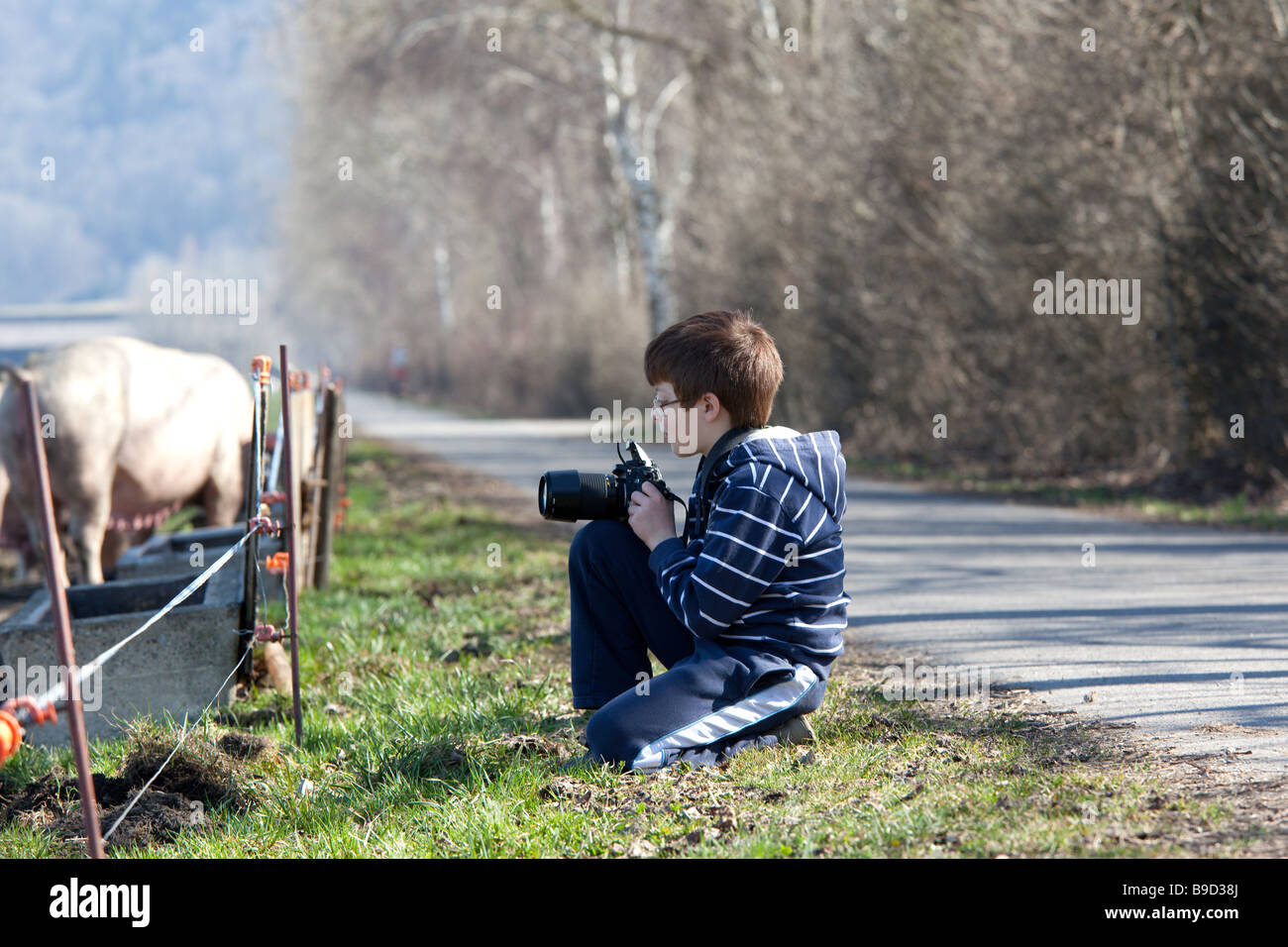 Young boy with a digital camera kneeling to take pictures of farm