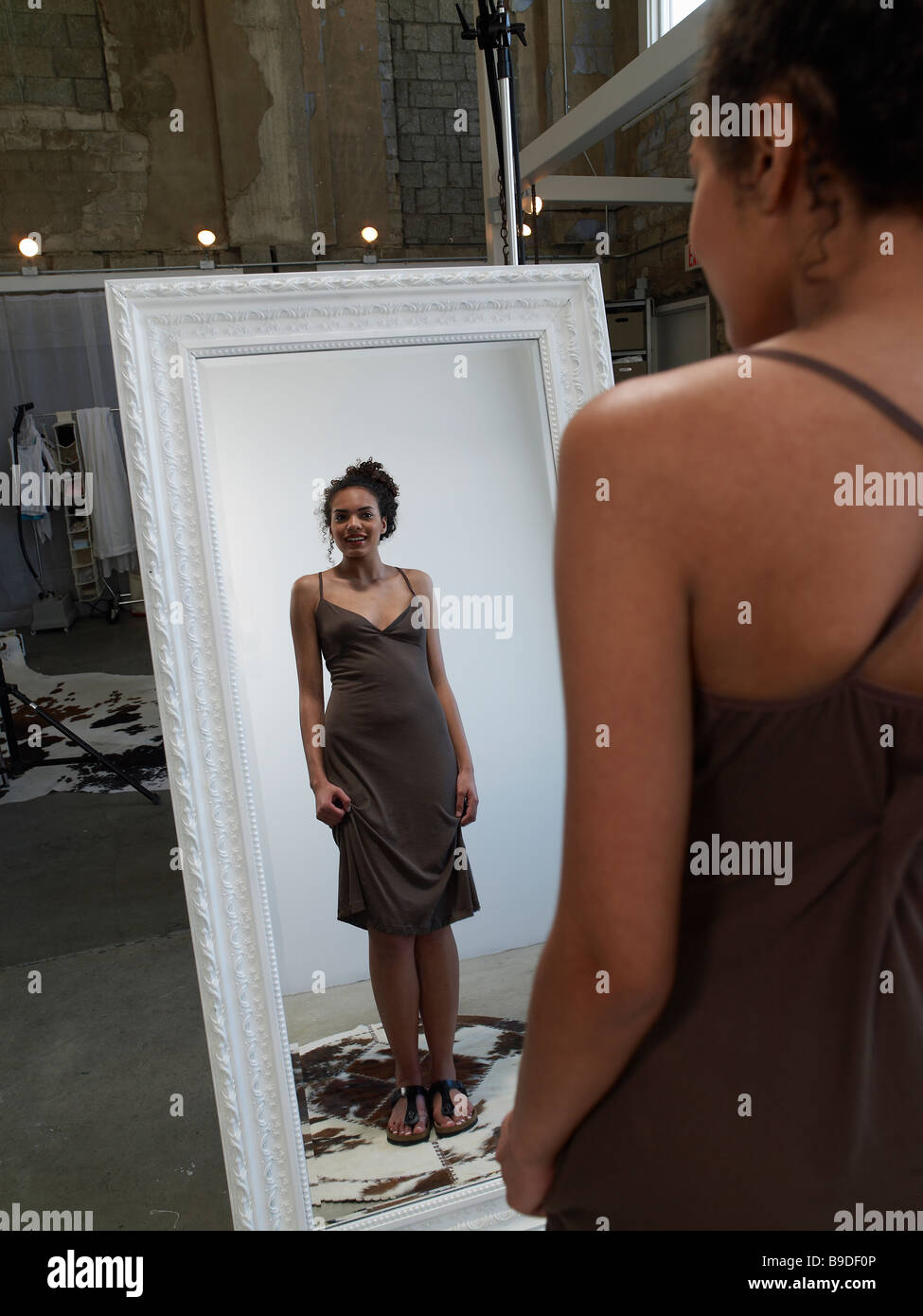 Woman looking at self with dress in front of mirror Stock Photo