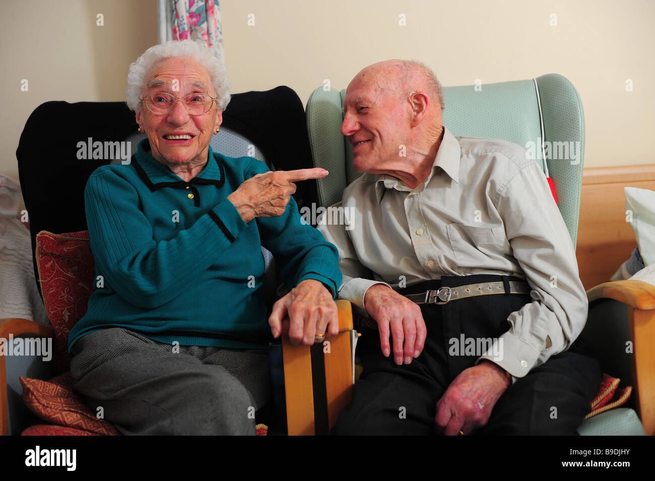 An elderly couple sitting laughing and happy in a nursing home. Stock Photo