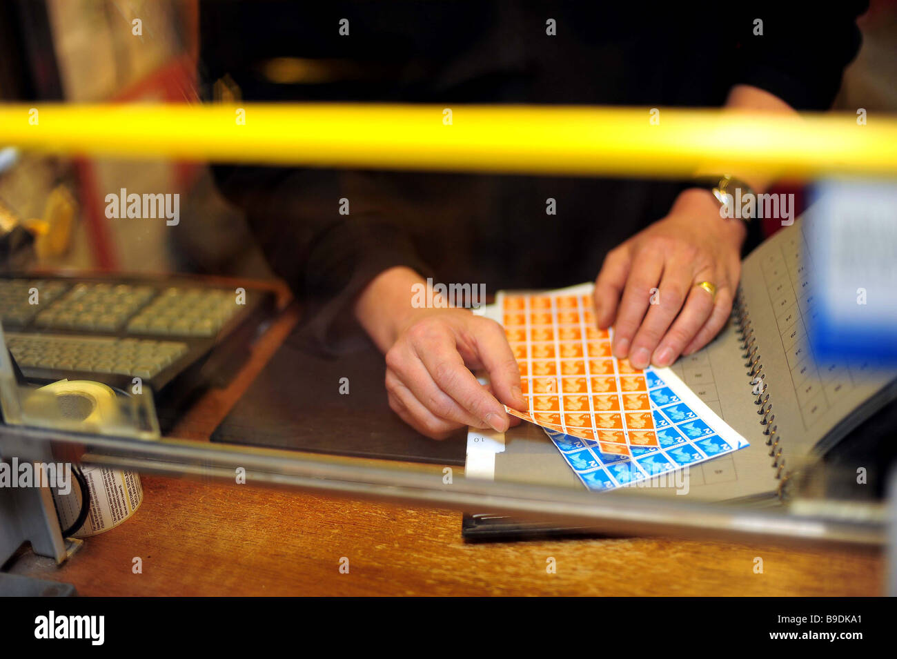 the hands of post office counter staff sorting and selling stamps at in