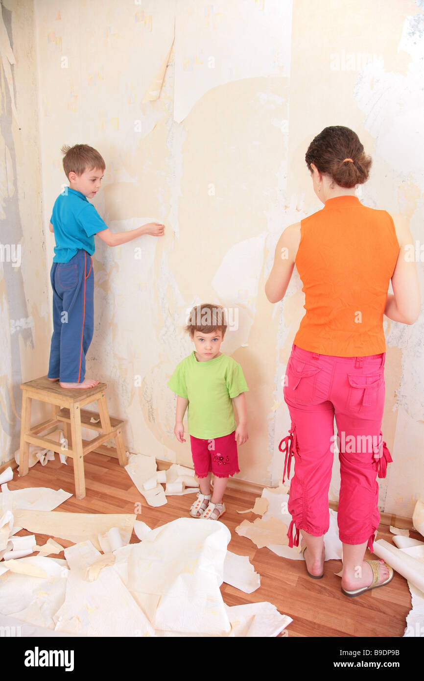 mother with children remove old wallpapers from wall Stock Photo Alamy