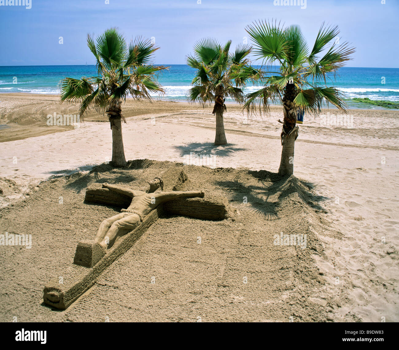Crucifix, sand art on Calp Beach, Calpe, palm trees, Costa Blanca, Alicante Province, Spain Stock Photo