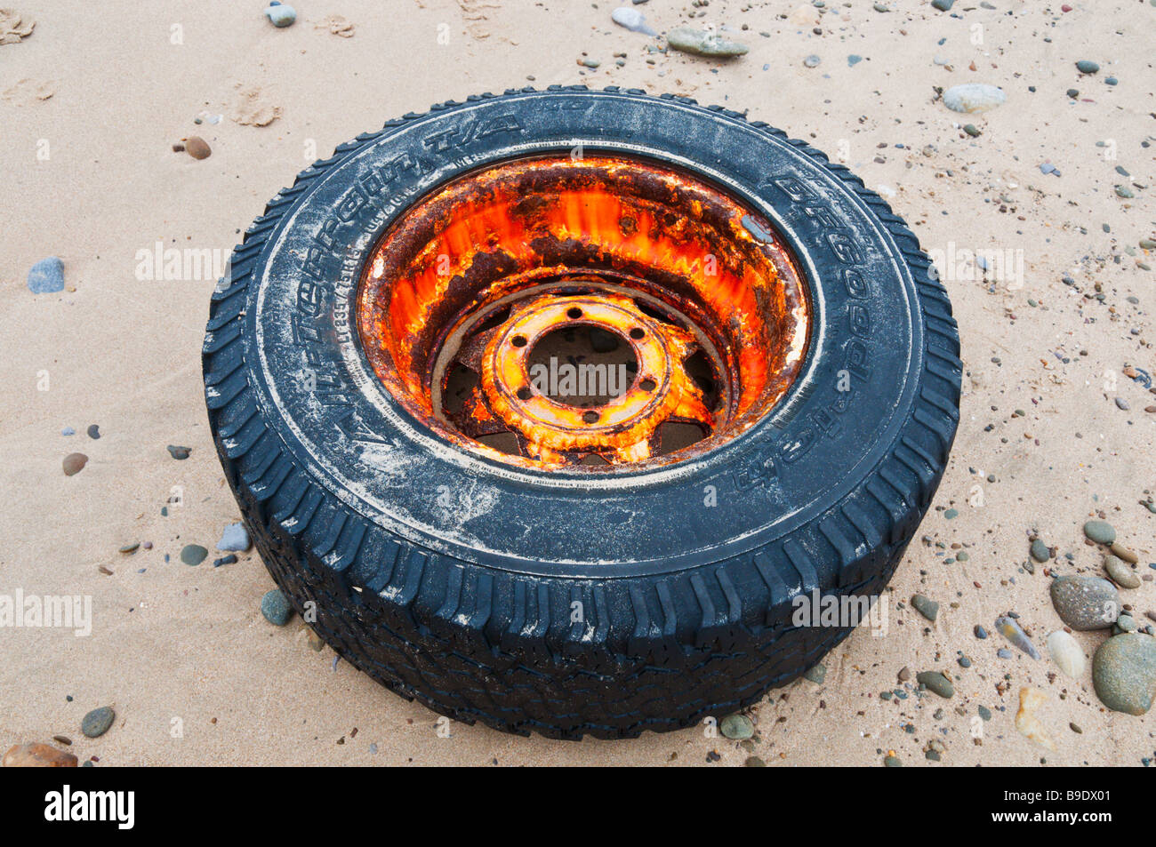 An old truck wheel and tyre washed up on a UK Beach Stock Photo