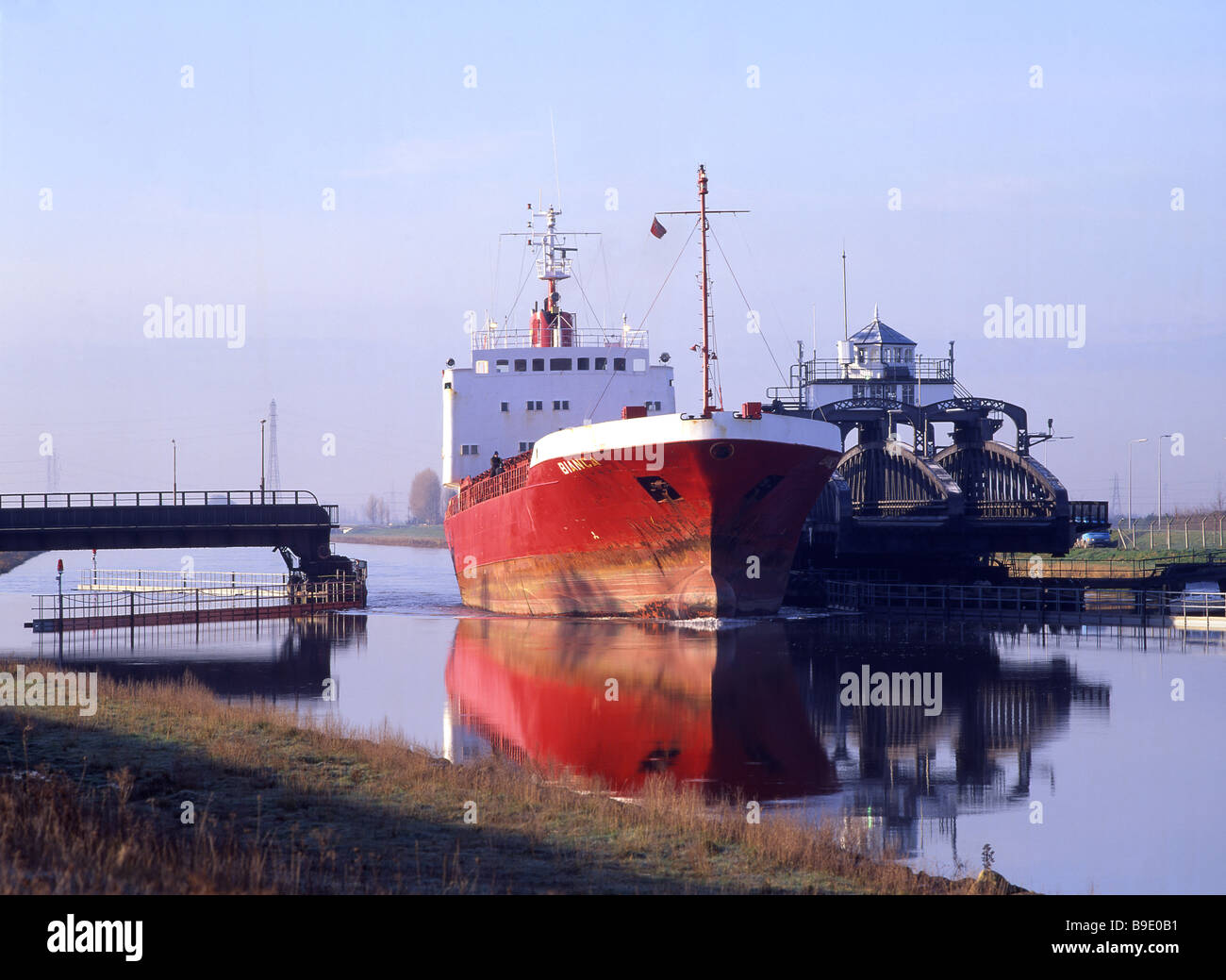 Ship passing through Sutton Bridge, Llincolnshire, on the River Nene on the way down river from the port of Wisbech, Cambs. Stock Photo