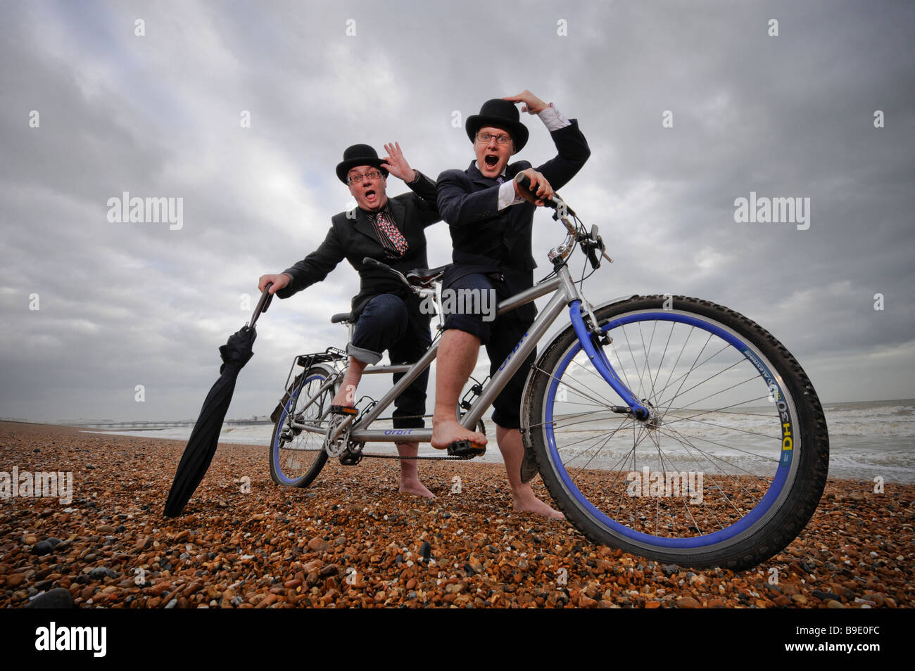 City gents limber up on Brighton beach with their tandem before competing in 'The Rat Race' event . Stock Photo
