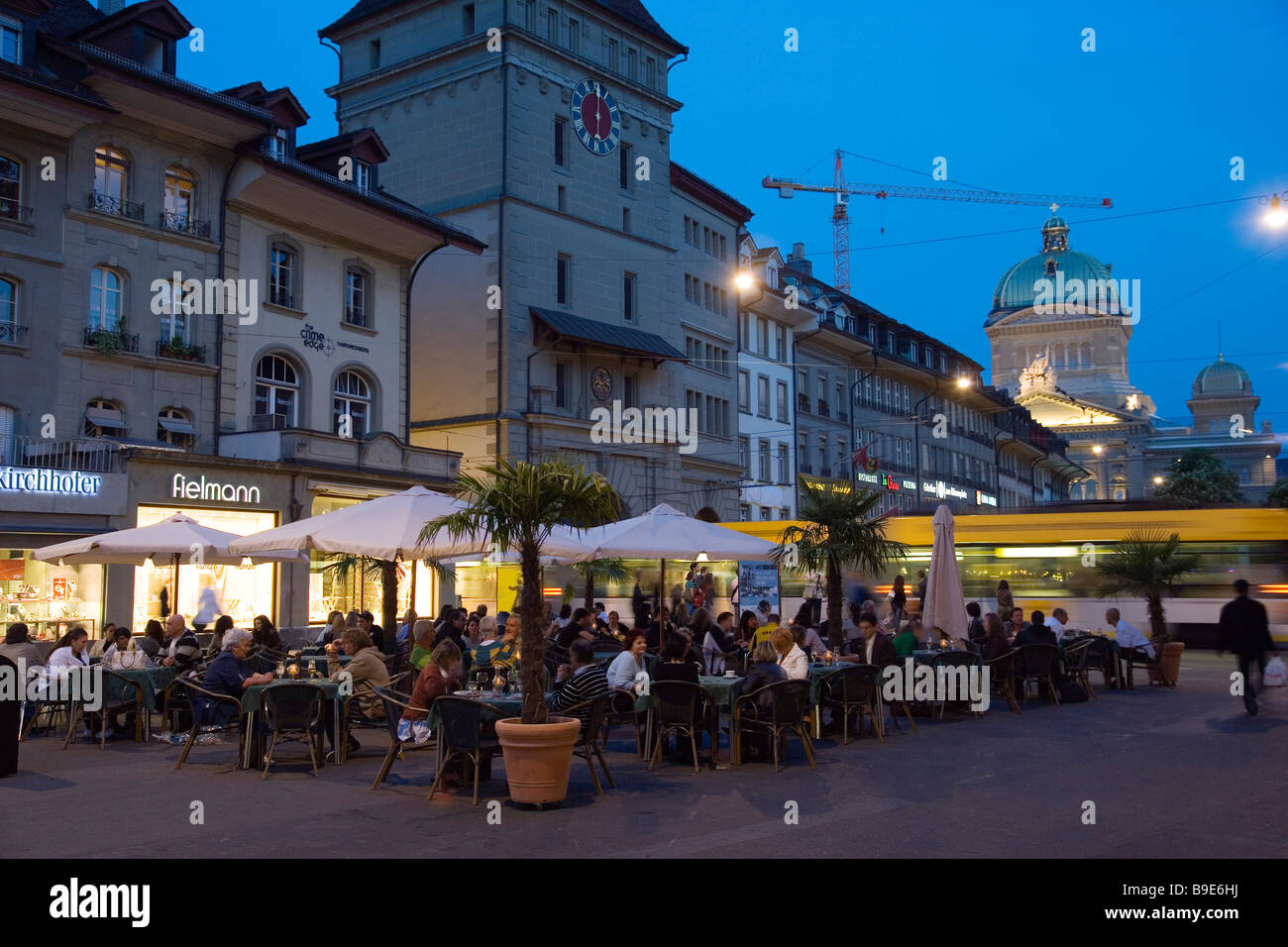 Guests sitting in pavement cafes at Bärenplatz in the evening Federal Palace in background Old Town Berne Stock Photo