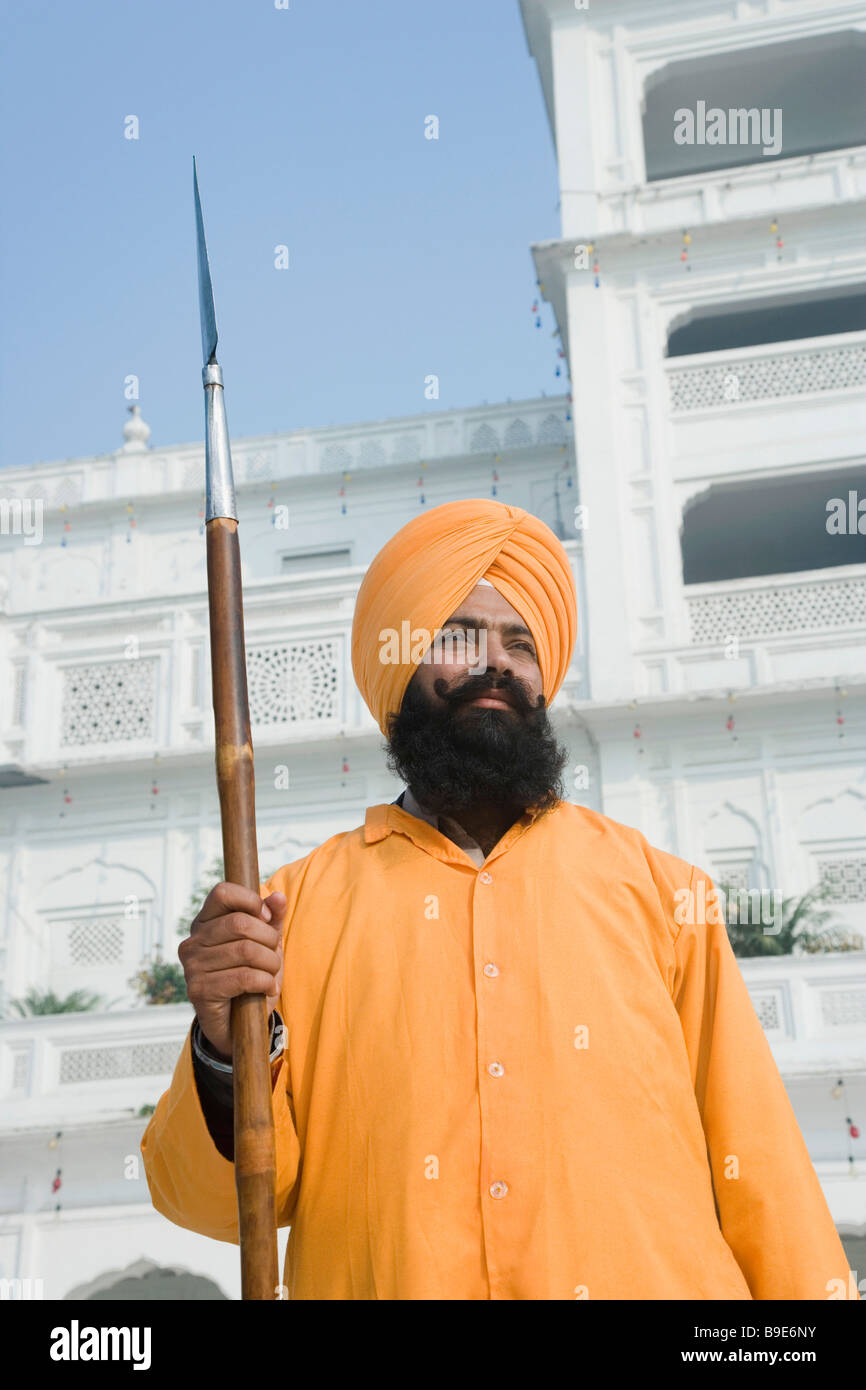 Man holding a spear in front of a temple, Golden Temple, Amritsar, Punjab, India Stock Photo