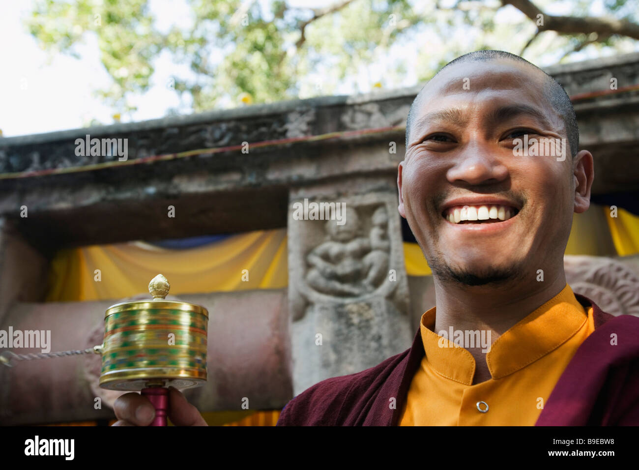 Monk holding a prayer wheel and smiling, Mahabodhi Temple, Bodhgaya, Gaya, Bihar, India Stock Photo