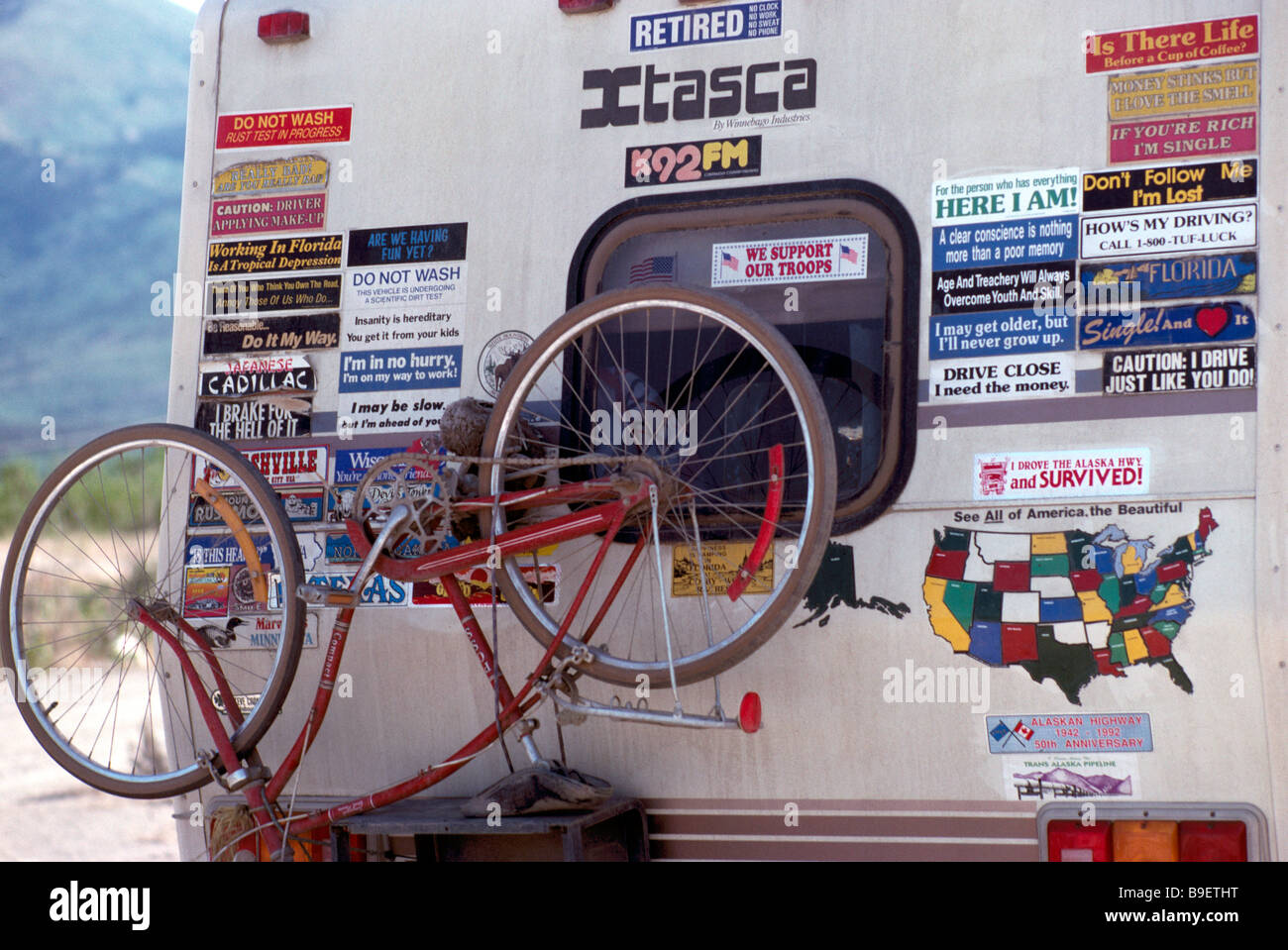 Bicycle and Funny Bumper Sticker Signs mounted on back of RV Recreational Vehicle Camper Stock Photo