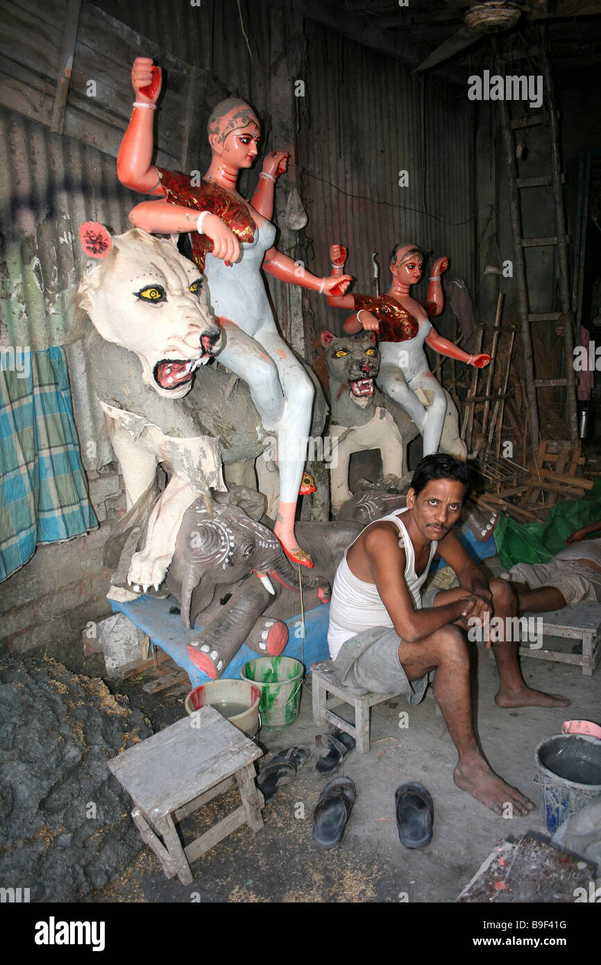 Artisan sits in his workshop beside a semi-painted Statue of Durga Riding Lion, Potters Market, Kumortuli, Kolkata Stock Photo