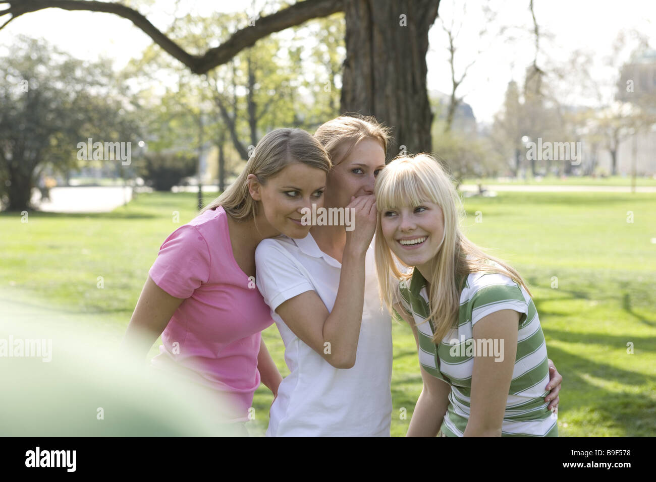 Park women three whispers cheerfully series people teenagers students students friends whispers cheerfully mysteriously Stock Photo
