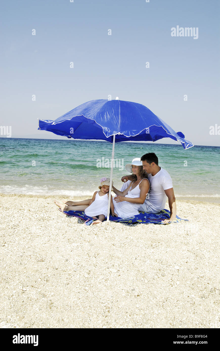 Family parasol beach sea 1 1/2 years 1-3 years 20-30 years 25-35 years 30-40 years relaxing bathing blue blue heaven three Stock Photo