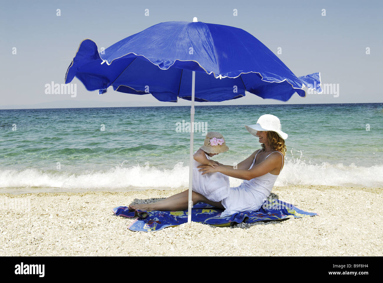 Mother daughter parasol beach sea 1 1/2 years 1-3 years 20-30 years 25-35 years single parent relaxing bathing blue blue heaven Stock Photo