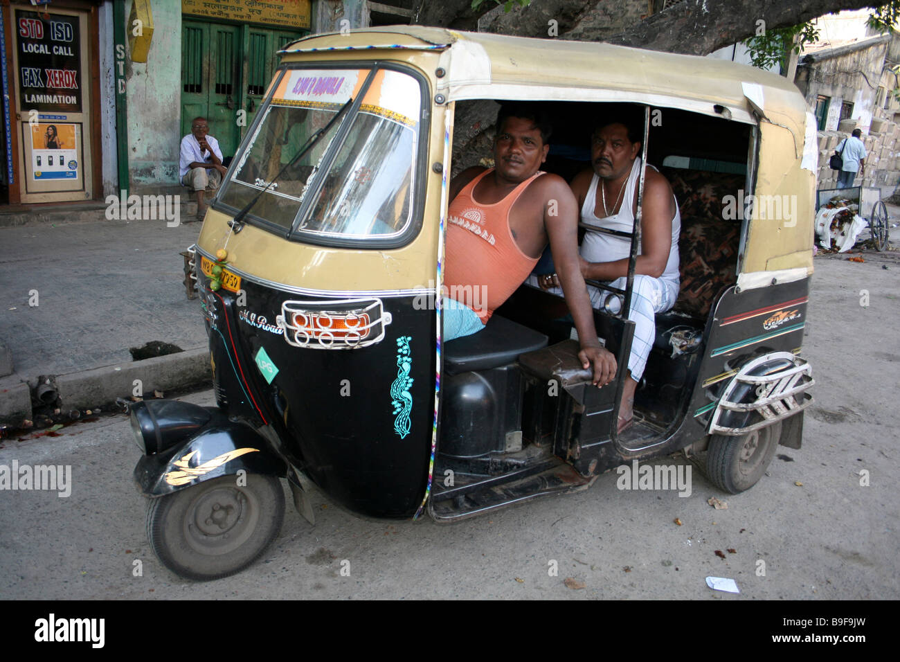 Indian Driver and Friend relaxing in their Tuc-tuc, Calcutta Street Stock Photo