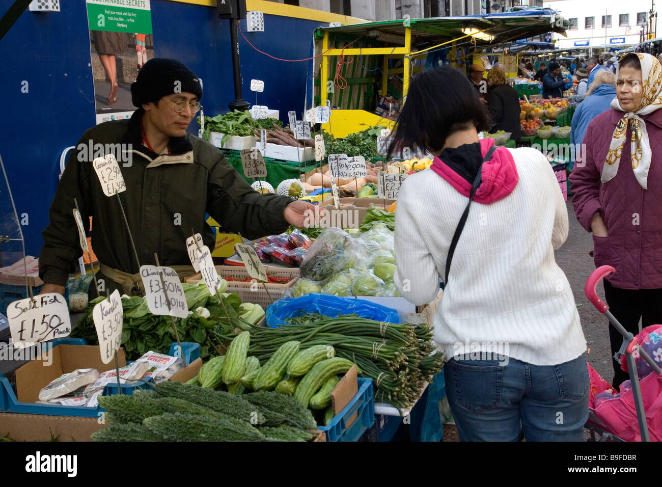 Chinese market trader selling produce in Surrey street market Croydon Surrey Stock Photo