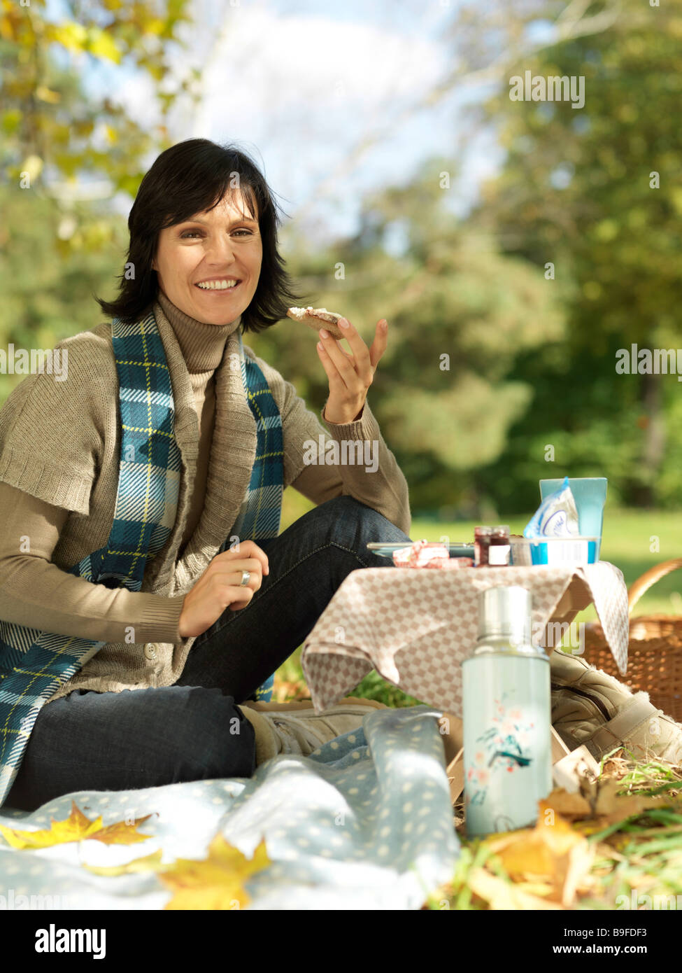Portrait of mature woman holding slice of bread and smiling in park Stock Photo