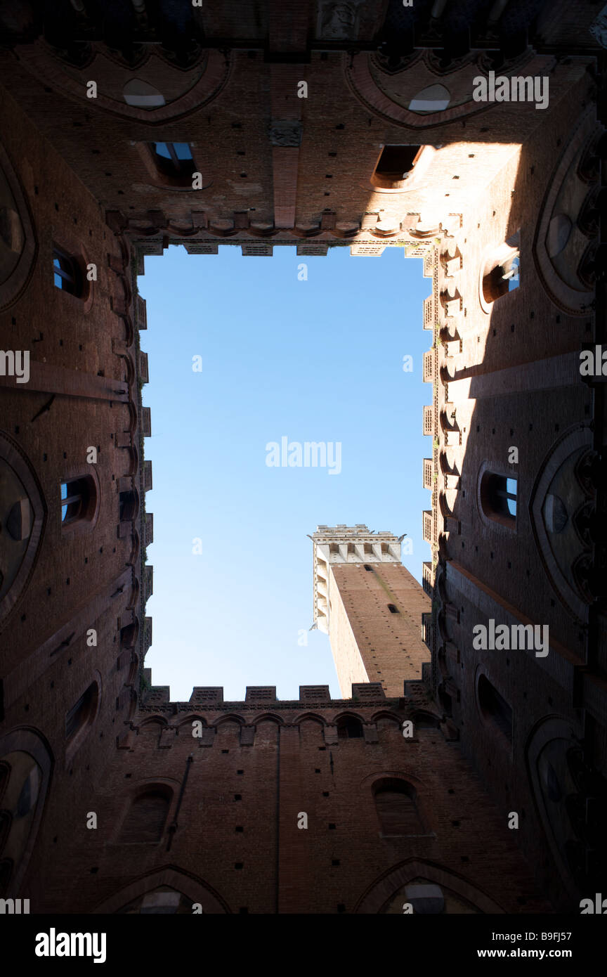 The view upwards to a blue sky from inside the La Torre del Mangia courtyard in Piazza del Campo Siena Italy Stock Photo