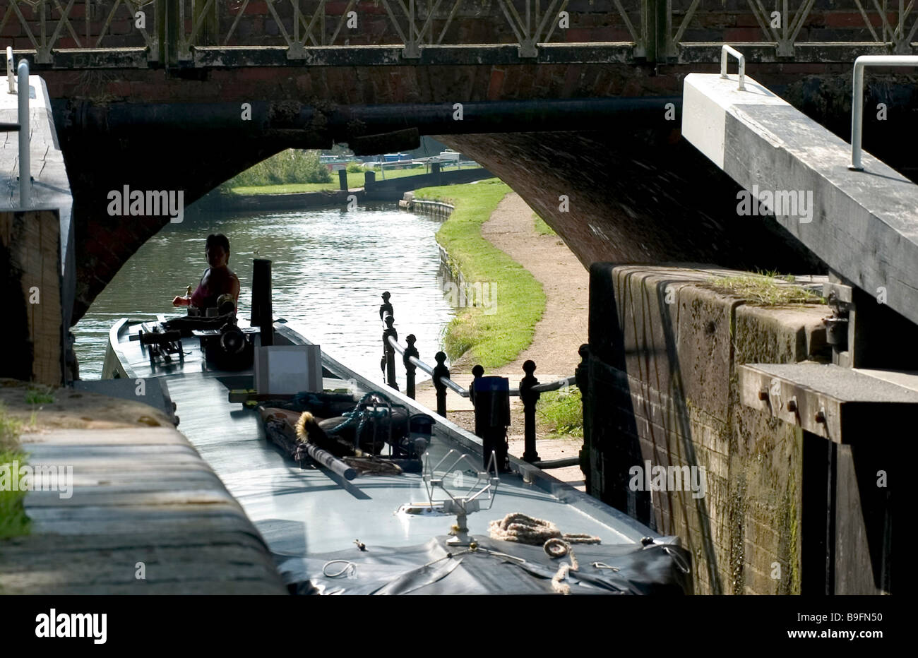 Canal boat travelling under bridge on river Stock Photo