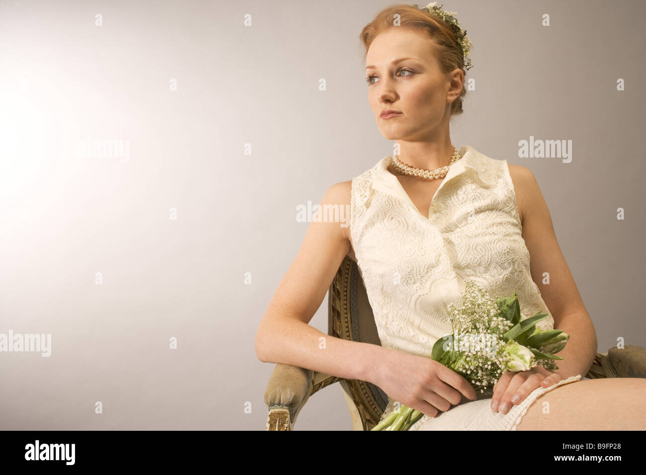 Woman flower-bouquet chair sitting  seriously thoughtfully gaze at the side 20-30 years red haired series bride wreath Stock Photo