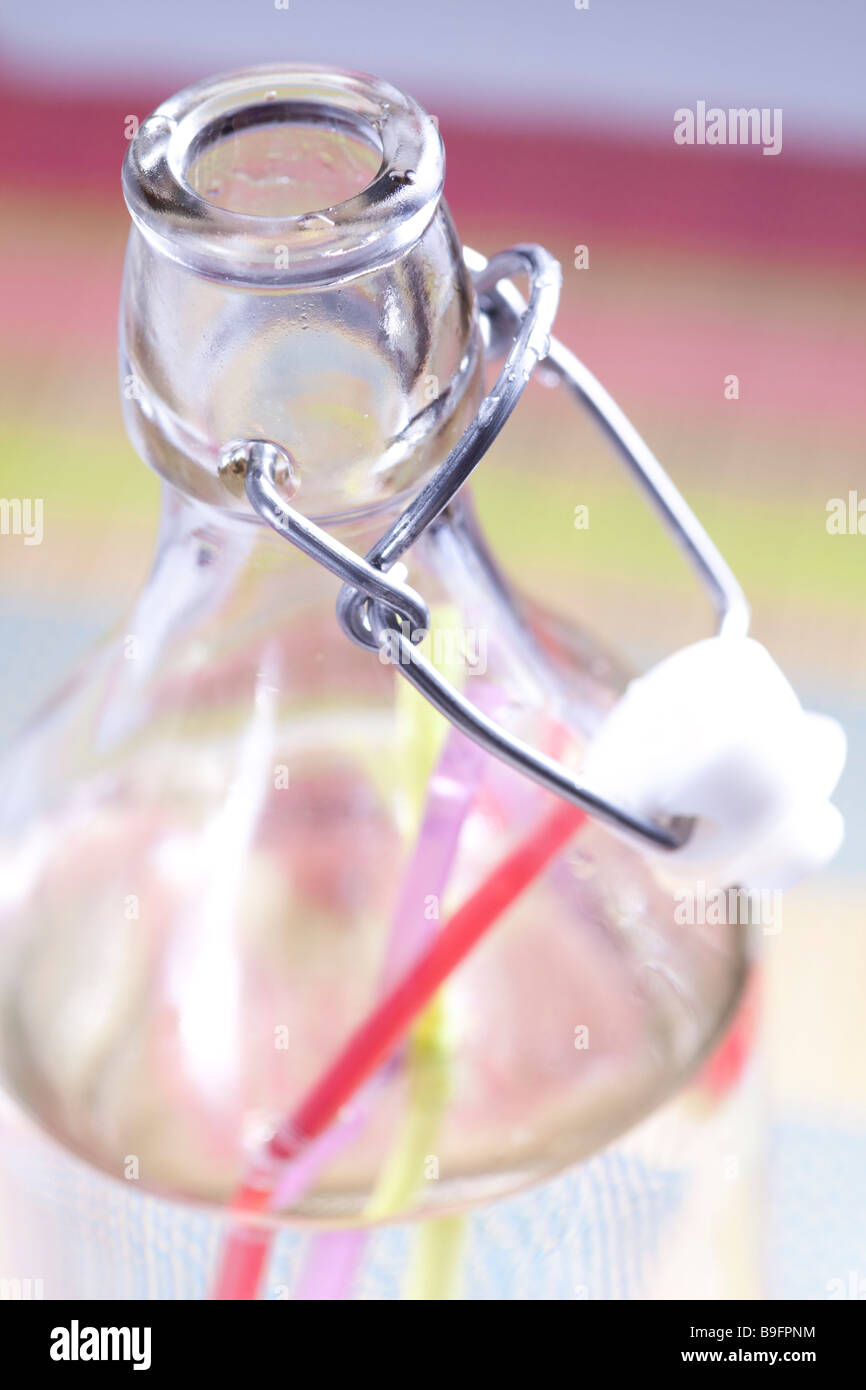 Glass bottle filled with water with 3 colorful straws inside Stock