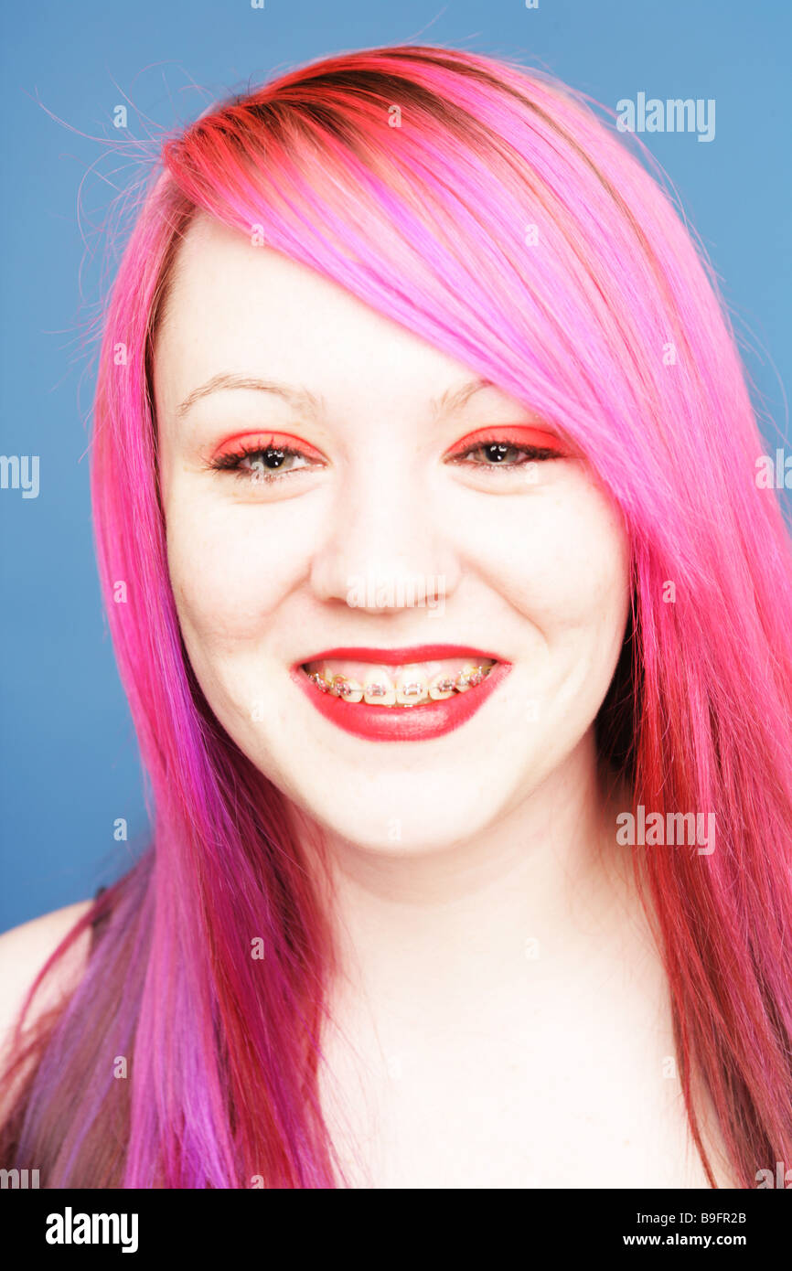 Young teen with bright pink hair wearing braces smiling at camera. Stock Photo