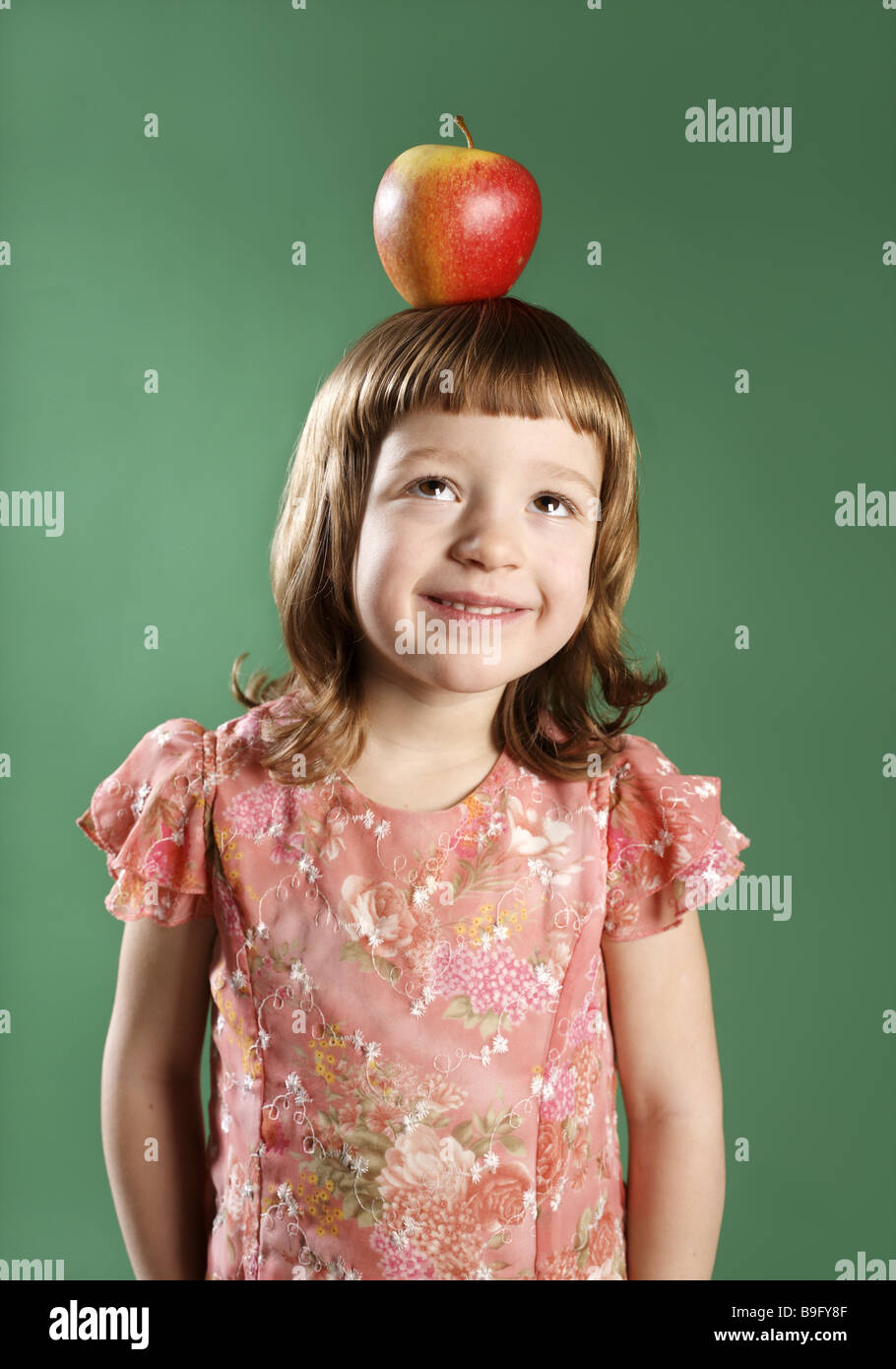 Child girl cheerfully 5-7 years balance head apple semi-portrait girls dark-blond dress happily cheerfully freely confidently Stock Photo