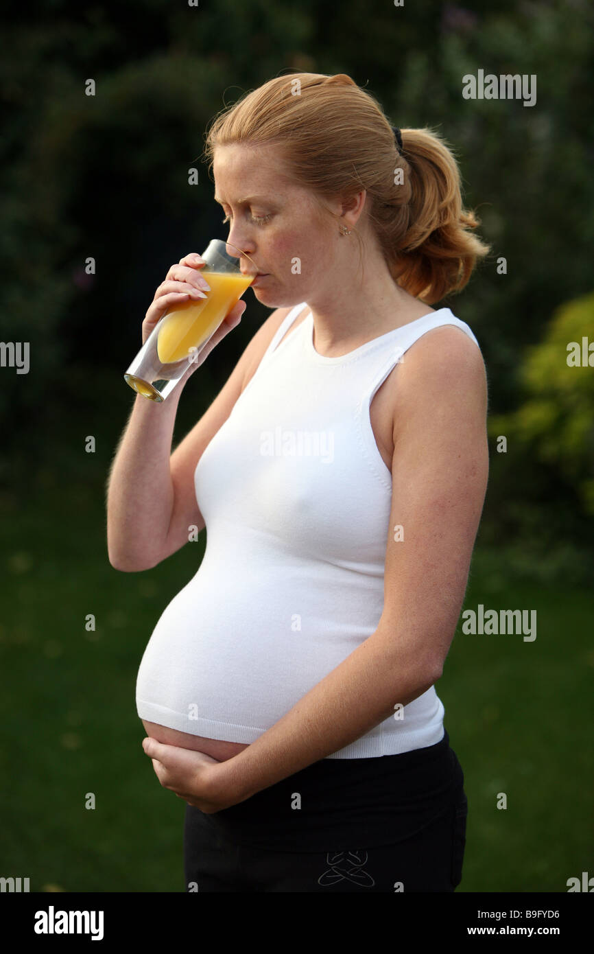 A pregnant woman drinking a glass of orange juice Stock Photo - Alamy