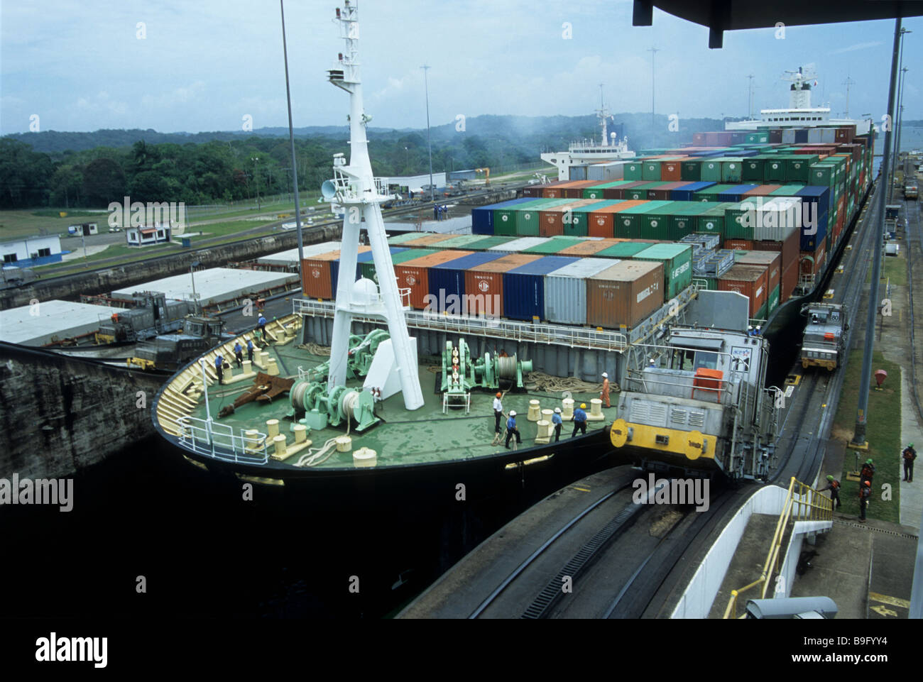 Container ship entering Gatun locks, Panama Canal. Train or 'mule' on RHS is guiding the ship Stock Photo