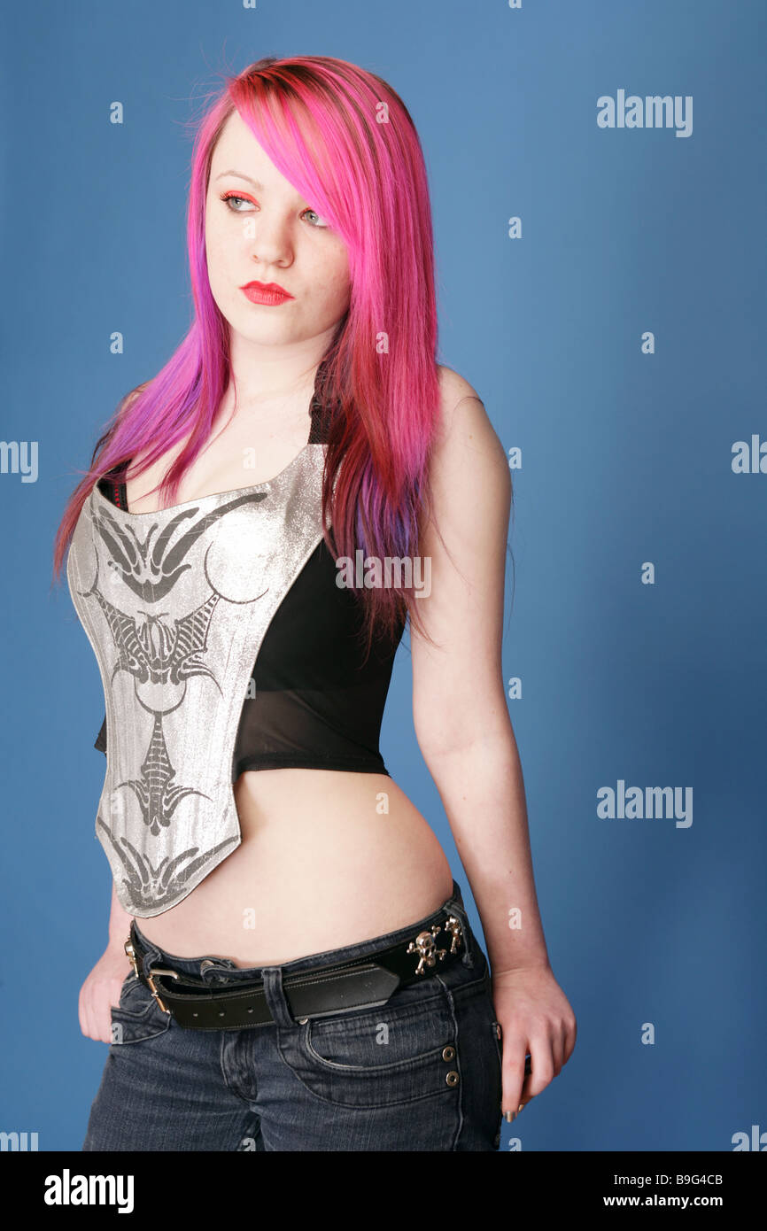 Young teen with bright pink hair red lips and pale skin standing with her thumbs in her jean pockets Stock Photo