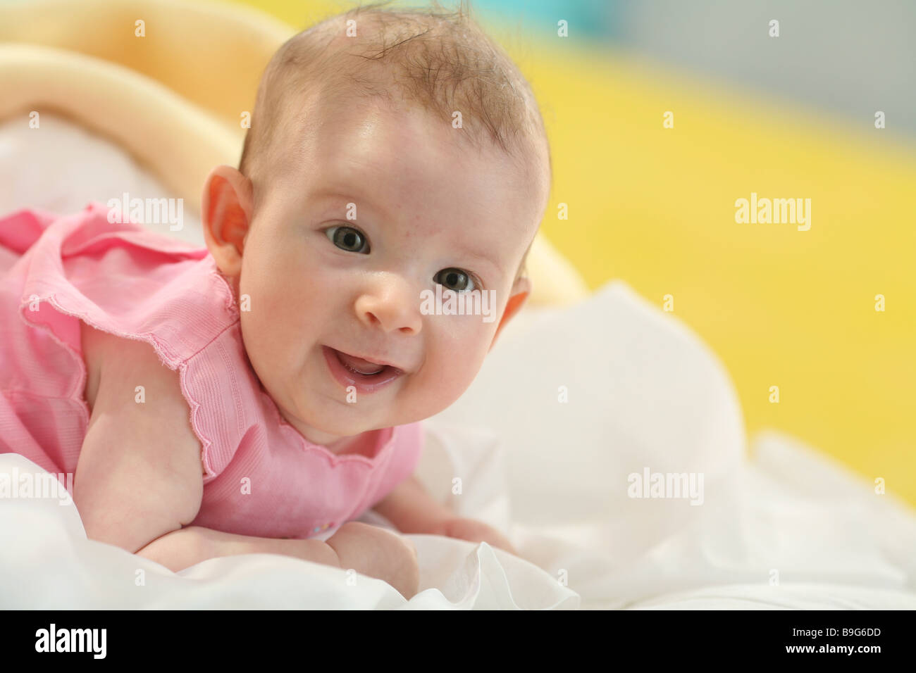 Baby lying prone position head lifts smiling portrait 4 months wakened resting baby observing prone position gaze camera one Stock Photo