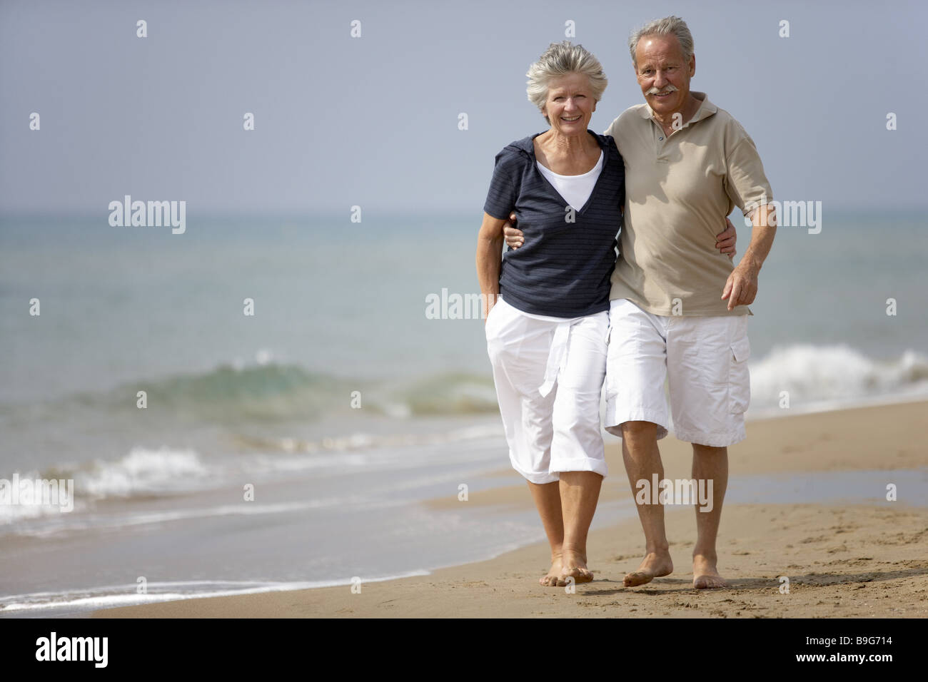 Fallen In Love Senior Couple Cheerfully Smiling Embrace Walk Barefoot Sandy Beach Lake Pension