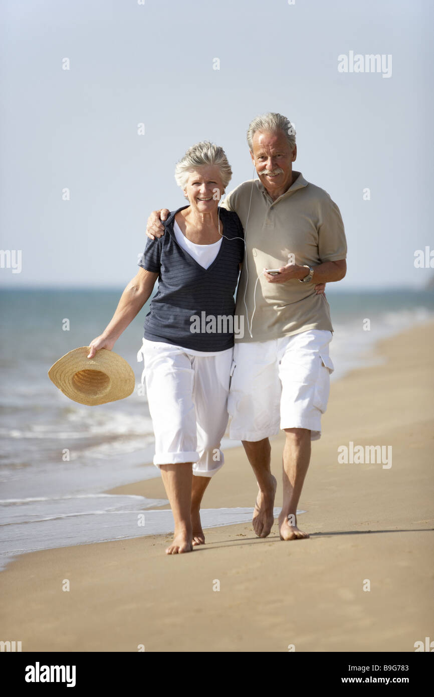 senior couple beach-walk music hears together MP3-Player cheerfully smile  barefoot beach sea pension retirement old age people Stock Photo - Alamy