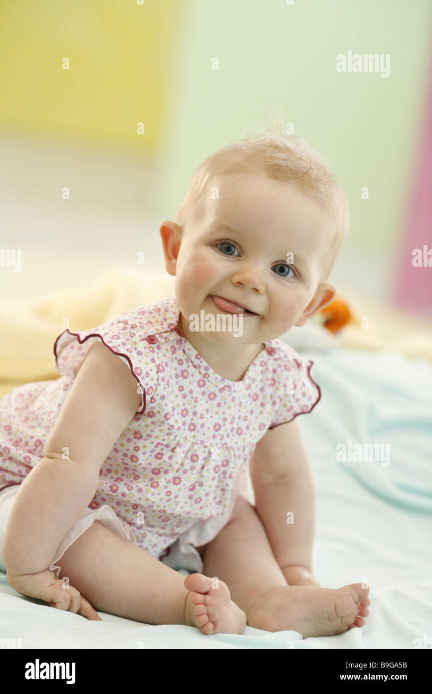Baby sitting expression tongue mouth full-length 8 months wakened alertly baby gaze camera one baby one person development joy Stock Photo