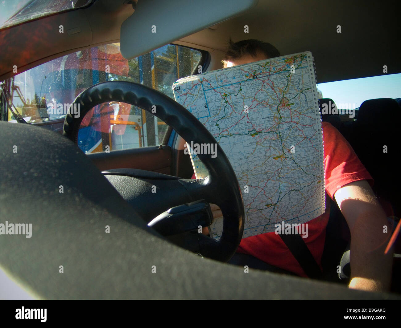 A car driver looks at the map whilst driving. Stock Photo