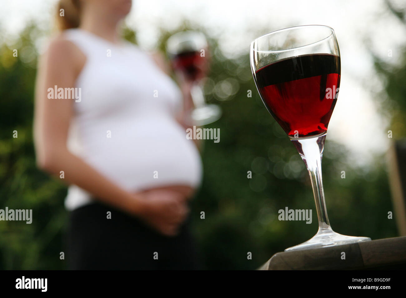 A glass of wine with a pregnant woman in the background Stock Photo Alamy
