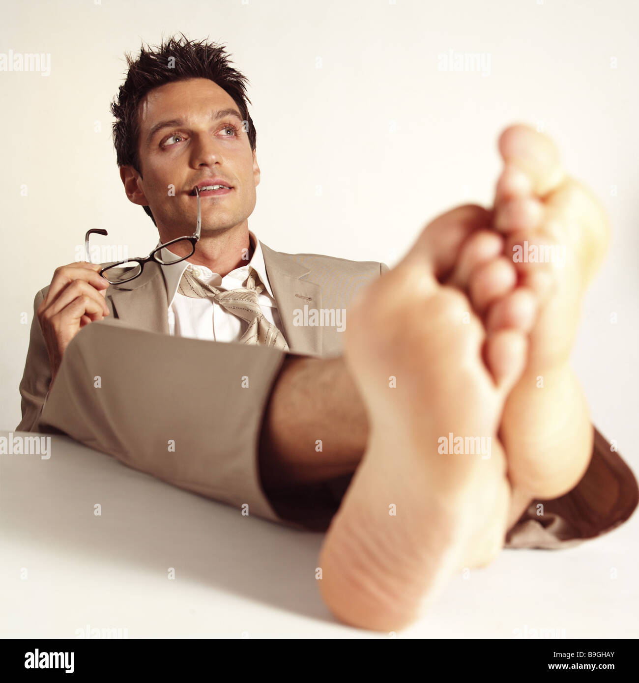 Managers barefoot feet puts up thinking series desk table people man 30-40 years glasses holding sitting  leans back feet Stock Photo