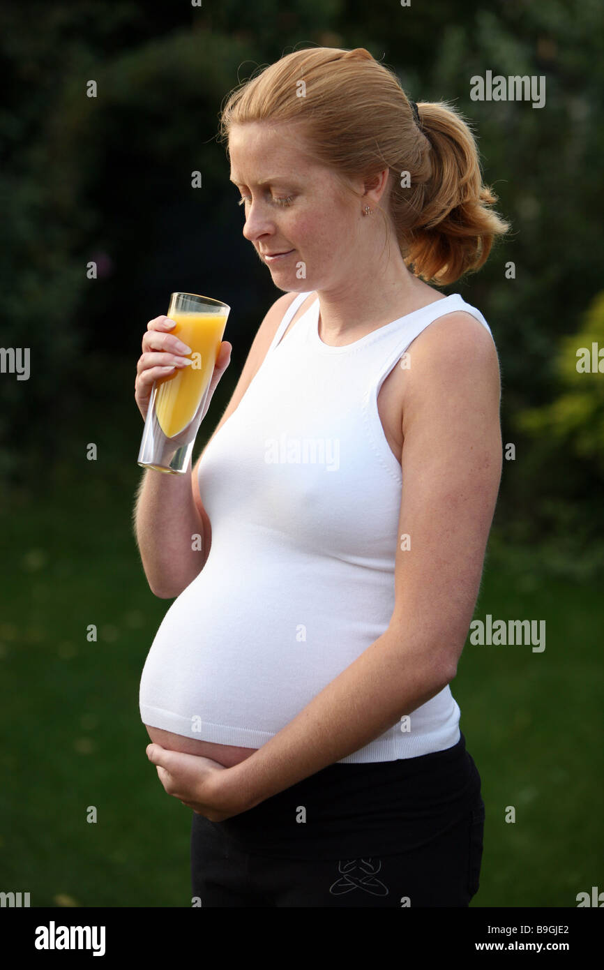 A pregnant woman with a glass of orange juice Stock Photo - Alamy