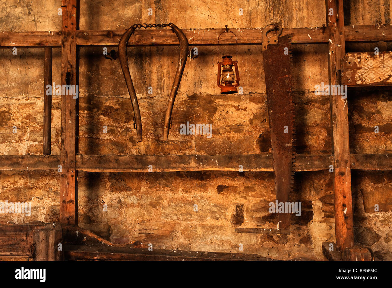 Old rusty tools hanging on stable wall Stock Photo