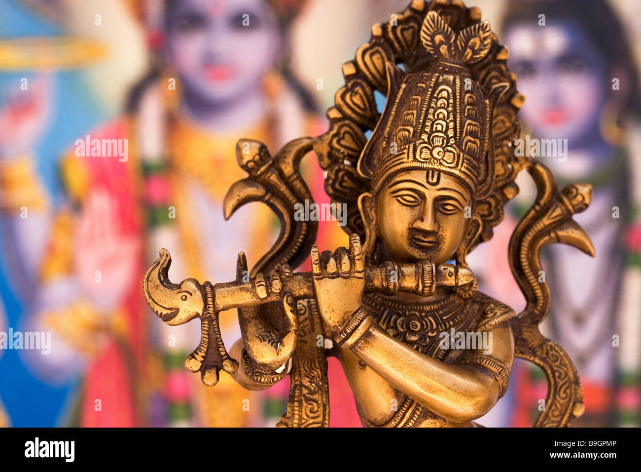 Metal Statue of Indian God Krishna Playing Flute with Colourful Indian Background Stock Photo