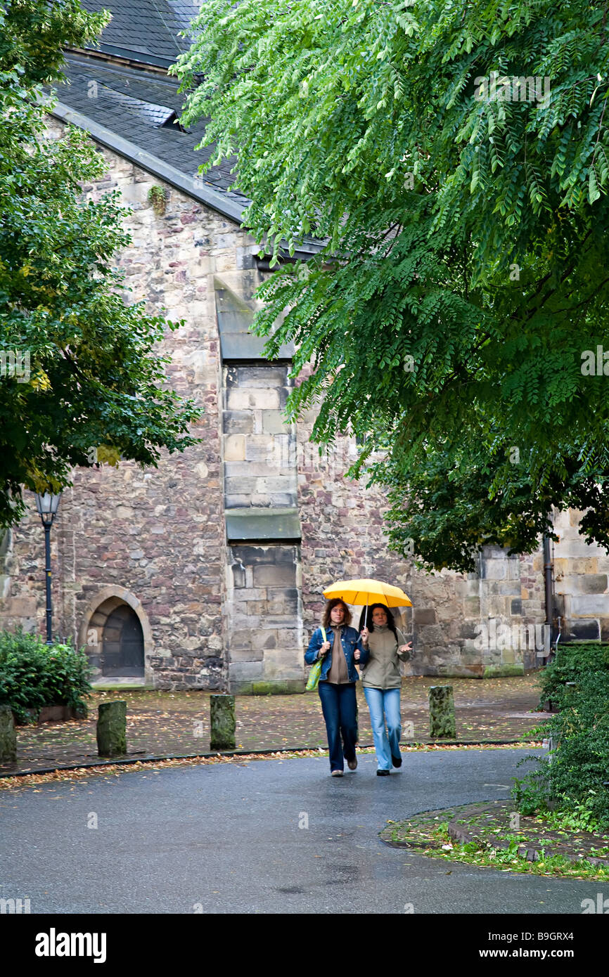 Two women walking in rain with umbrella Hamelin Germany Stock Photo