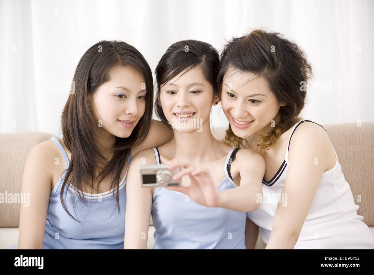 Three young women photographing themselves smiling portrait Stock Photo ...