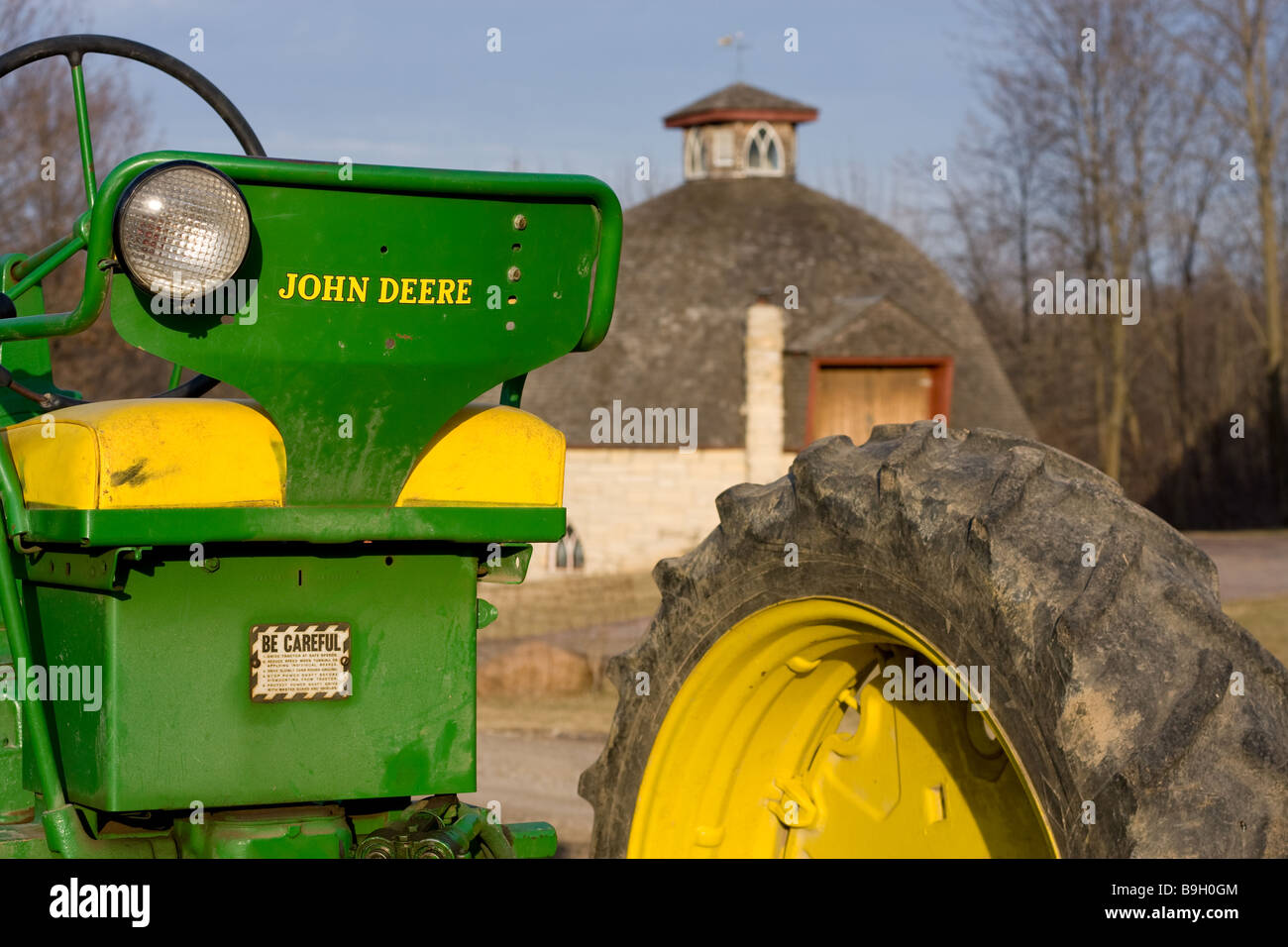 John Deere tractor with round barn in background Stock Photo