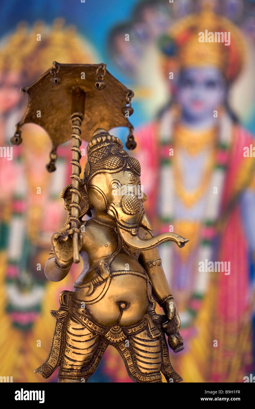 Metal Statue of Indian God Ganesh holding Umbrella with Colourful Indian Background. Ganesh is also known as Ganapati & Vinayaka Stock Photo